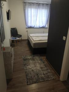 Schlafzimmer mit einem Bett, einem Fenster und einem Teppich in der Unterkunft Pension Forstfeld Kassel in Kassel