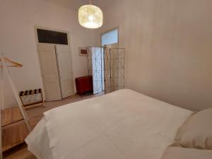 a bedroom with a white bed and a chandelier at Estúdio na Carreira in Elvas