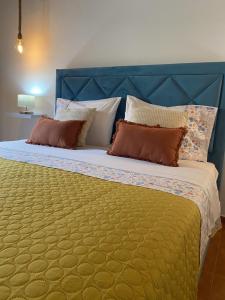 a large bed with a blue head board and pillows at Cantinho do Sol in Mosteiros