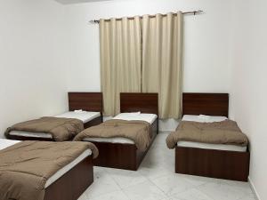 trzy łóżka siedzące w pokoju z zasłonami w obiekcie Short Tourist Place w Dubaju