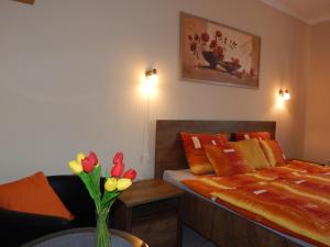 a bedroom with a bed and a vase of flowers on a table at Völgy Apartman in Eger