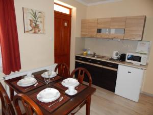 une petite cuisine avec une table en bois, une table et des chaises dans l'établissement Völgy Apartman, à Eger