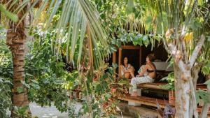 two women sitting on a bench in a garden at Dos Aguas Lodge in Rincón
