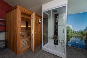 una ducha con una puerta de cristal junto a un cuerpo de agua en CicloLodge, en Lozoya