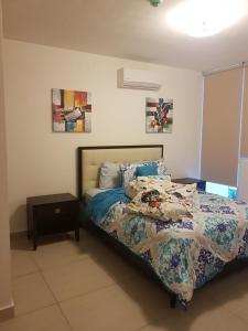 a bedroom with a bed with a comforter and a table at Alquiler de Apartamento en Playa Blanca in Río Hato