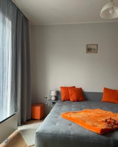 a bedroom with a bed with an orange blanket on it at Stan na dan Oplenac in Topola
