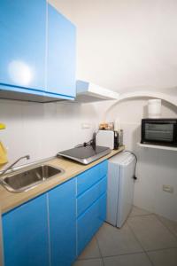 uma cozinha com armários azuis, um lavatório e um micro-ondas em ELISA Dependance Centro em Vietri
