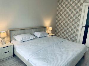 1 cama con 2 almohadas blancas y 2 mesitas de noche en Yas Apartment en Samarcanda