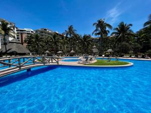 a large pool with a bridge and palm trees at Beachfront 2 bedroom Condo in Playa Royale Resort, Nuevo Vallarta in Nuevo Vallarta 