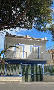 una casa blanca con una valla azul en Villa GLORIA intero alloggio sulla spiaggia 8 posti letto 15 minuti da Palermo e 35 da Cefalu, en Casteldaccia