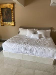 uma cama com lençóis brancos e almofadas num quarto em Hotel Gya Express em Aguascalientes