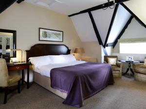 Schlafzimmer mit einem Bett, einem Schreibtisch und Stühlen in der Unterkunft Macdonald Bear Hotel in Woodstock