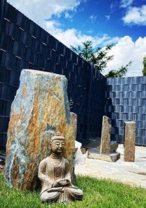 a statue of a buddha sitting next to a rock at Villa Dreamy Vibes mit Privatem Pool & Rheinblick in Niederkassel