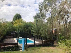 una piscina en un patio con bancos y árboles en Maia en Tigre