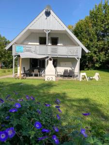 ein großes weißes Haus mit Stühlen und lila Blumen in der Unterkunft Ferienhaus am Silbersee Leni in Frielendorf