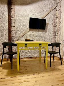 żółty stół z dwoma krzesłami i telewizorem w obiekcie The House a la Cluj w Klużu-Napoce