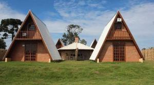 a house with a triangular roof on top of a field at Hotel Rancho XV in Itapeva