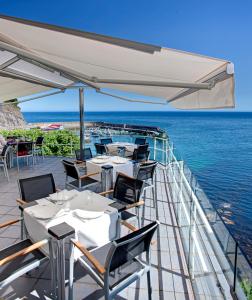 a dining room table with chairs and umbrellas at Hotel Lastres Miramar in Lastres