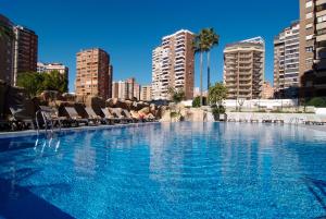 una gran piscina con sillas y edificios en Sandos Monaco - Adults Only, en Benidorm