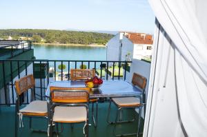 einen Tisch und Stühle auf einem Balkon mit Blick auf das Wasser in der Unterkunft Piso en Urbanización Villarchao in O Grove