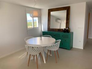 Biały stół i krzesła w pokoju z lustrem w obiekcie Beautiful apartment with pool near the beach w mieście Oliva