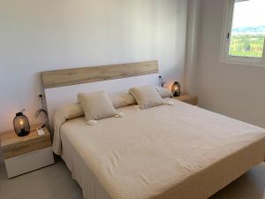 biała sypialnia z dużym łóżkiem z 2 lampami w obiekcie Beautiful apartment with pool near the beach w mieście Oliva