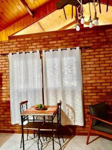 mesa y sillas en una habitación con 2 ventanas en Chalés Alcantilado - Morada Sol e Lua, en Visconde De Maua
