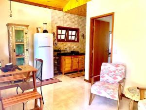 a kitchen with a refrigerator and a table and a chair at Chalés Alcantilado - Morada Sol e Lua in Visconde De Maua