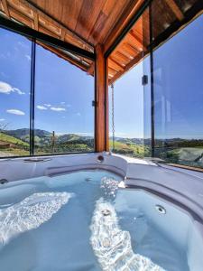 a hot tub in a room with a large window at Chalés Conforto Mineiro in Gonçalves