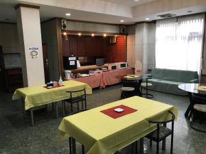 un restaurante con mesas y sillas amarillas y un sofá en Biz Hotel Kiiyura, en Yura