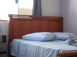 a bed with a wooden headboard and two pillows on it at Pousada Santa Maria in Aparecida +46 photos