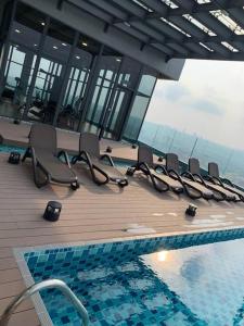 a row of chairs sitting next to a swimming pool at 2BR 8pax SwingDuplexEkocherasMall—InfinityPool MRT in Kuala Lumpur +95 photos