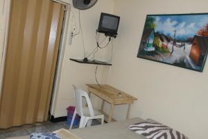 a bedroom with a desk and a tv on the wall at Hostal Nicaragua Guest House in Managua