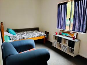 1 dormitorio con 1 cama y 1 silla azul en Warren Retreat - cozy and tranquil 2 brm home, en Nannup