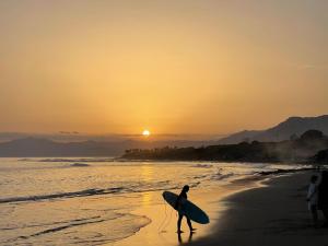 a person walking on the beach with a surfboard at Marbella Deluxe Rooms in Royal Cabopino Townhouse in Marbella