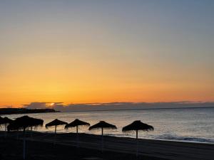 a group of umbrellas on the beach at sunset at Marbella Deluxe Rooms in Royal Cabopino Townhouse in Marbella