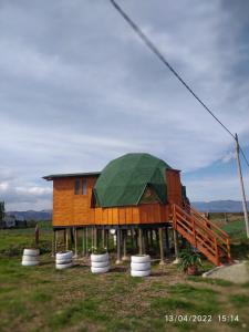 a house with a green roof on a field at Glamping y Cabañas el Encanto- los novios in Tota