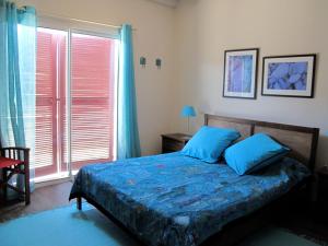 a bedroom with a bed with blue sheets and a window at Apitoki - Chambres d'hôtes au Pays Basque in Urrugne