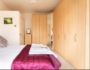 a bedroom with a large bed with a pink blanket at Shelley’s Seaside Stay (Garden/ Double Drive) in Porthcawl