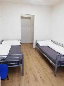 two beds in a room with a wooden floor at Ubytovňa Nobelova in Bratislava