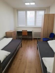 a room with two beds and a desk and a chair at Ubytovňa Nobelova in Bratislava