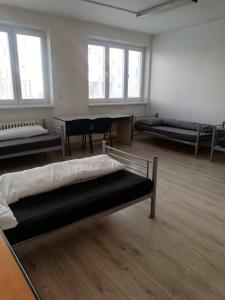 Habitación con 3 camas y mesa. en Ubytovňa Nobelova, en Bratislava