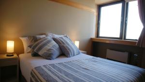 a bedroom with a bed with pillows and a window at Red Fox Lodge Myoko in Myoko