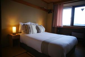 1 dormitorio con 1 cama con lámpara y ventana en Red Fox Lodge Myoko en Myoko