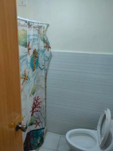 y baño con cortina de ducha y aseo. en Sunmiles Condominium en Calamba