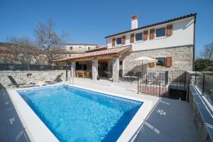 a villa with a swimming pool in front of a house at Villa Poji in Buzet