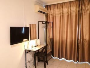 Habitación con escritorio, TV y mesa con silla. en G Star Motel, en Kuching