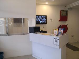 un mostrador blanco en una habitación con TV en la pared en G Star Motel, en Kuching
