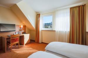 a hotel room with a bed and a desk and a window at Berggasthof Banzer Wald in Bad Staffelstein