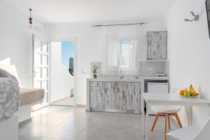 a white kitchen with a table and a counter at IL Vento Suites in Mikonos
